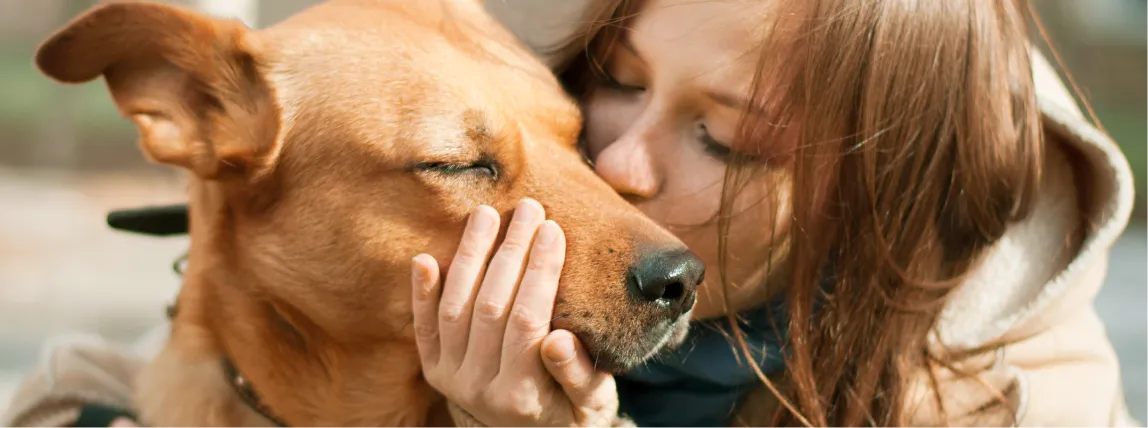 Ein Hund wird von seinem Frauchen geküsst.