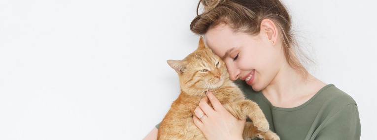 Eine Frau hält ihre Katze auf dem Arm und schmust mit ihr.