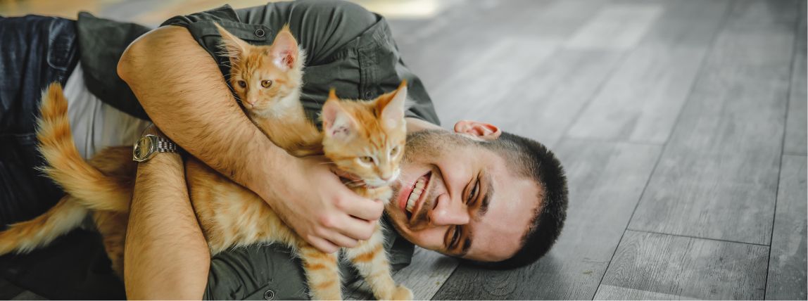 Ein Katzenbesitzer schmust mit seinen Katzen, die beide bei petolo versichert sind.