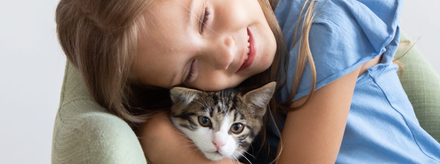 Ein Mädchen kuschelt mit einem Kitten.